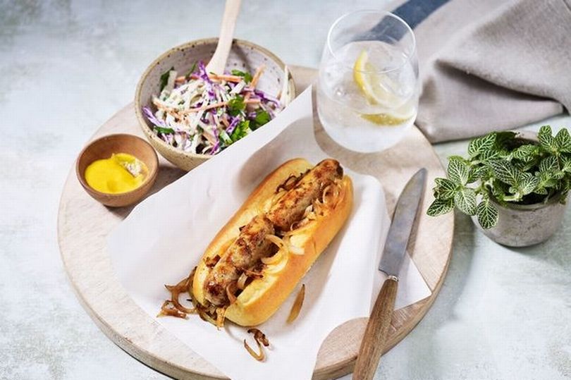 Hot dog, bowl of coleslaw, bowl of mustard and a drink on a tray.