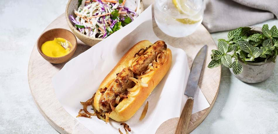 Hot dog, bowl of coleslaw, bowl of mustard and a drink on a tray.