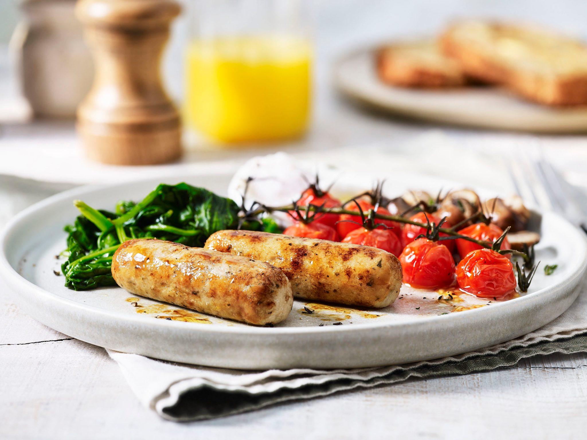 Sausages, tomatoes and spinach on a plate.