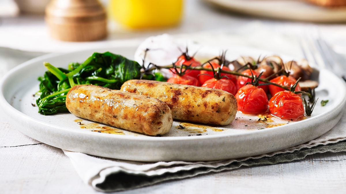 Sausages, tomatoes and spinach on a plate.